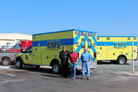 Three men standing next to an EMS van